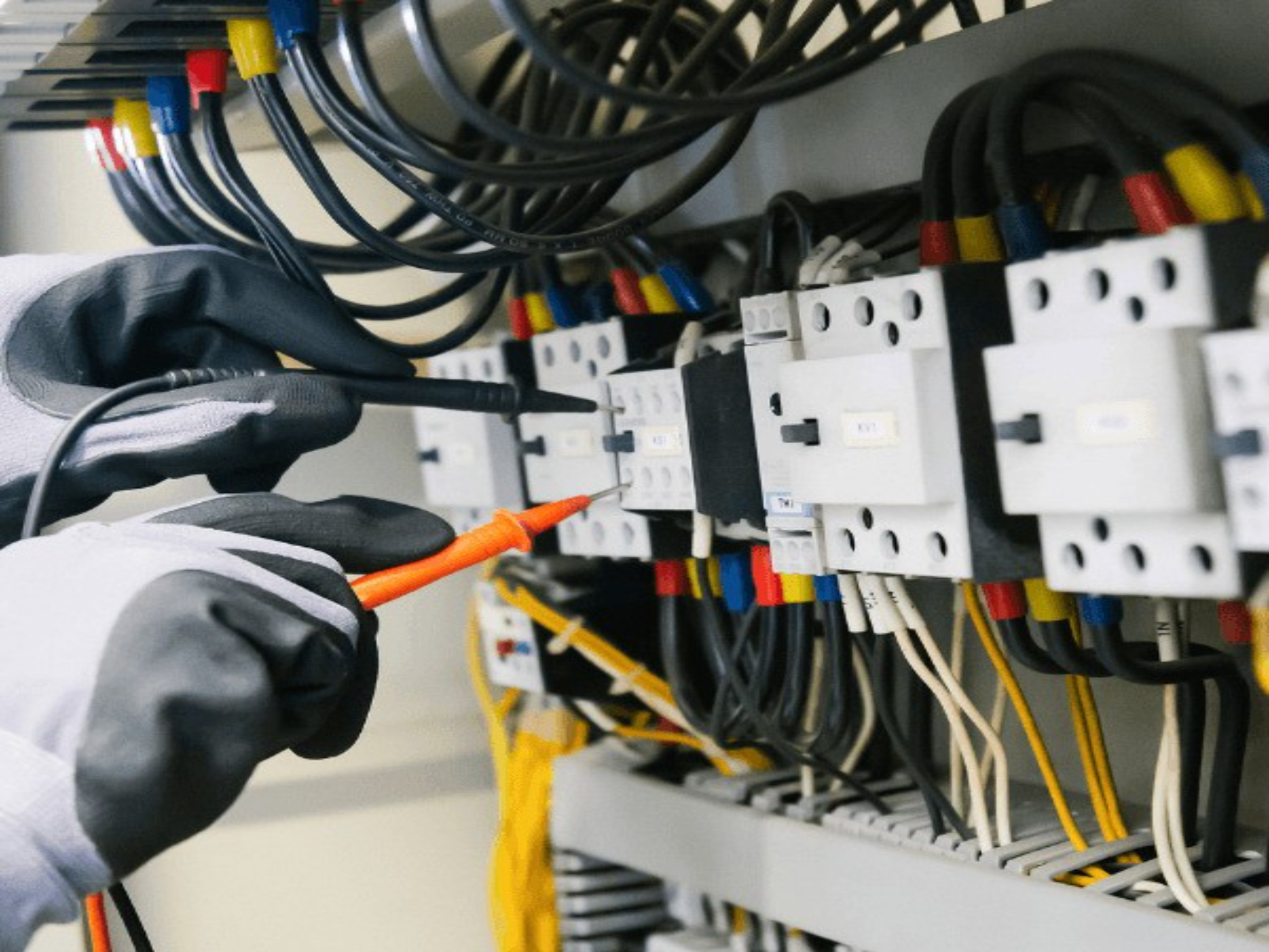Electrician testing a commercial electrical cabinet with meter probes